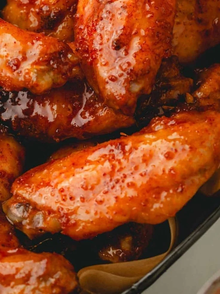 Delicious hot honey chicken wings garnished with herbs on a serving platter.