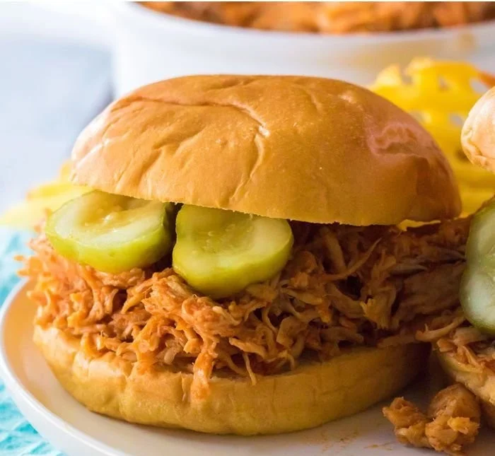 Slow Cooker Chicken Sandwich topped with Hot Honey on a rustic plate